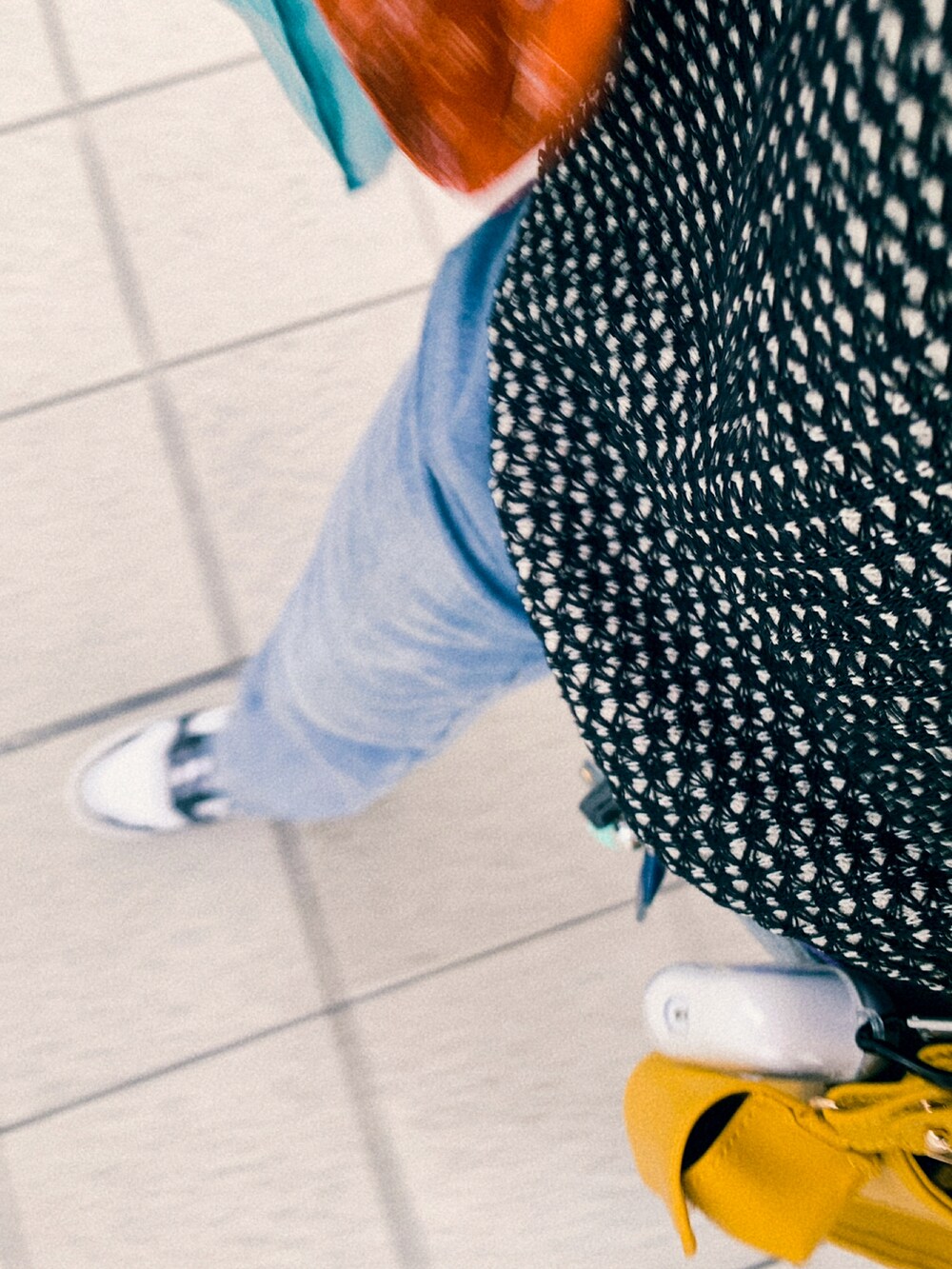 ホワイト系のスニーカー、ブルー系のデニムパンツ、ブラック系のポロシャツを着用したレディースの冬コーディネートの2枚目の写真