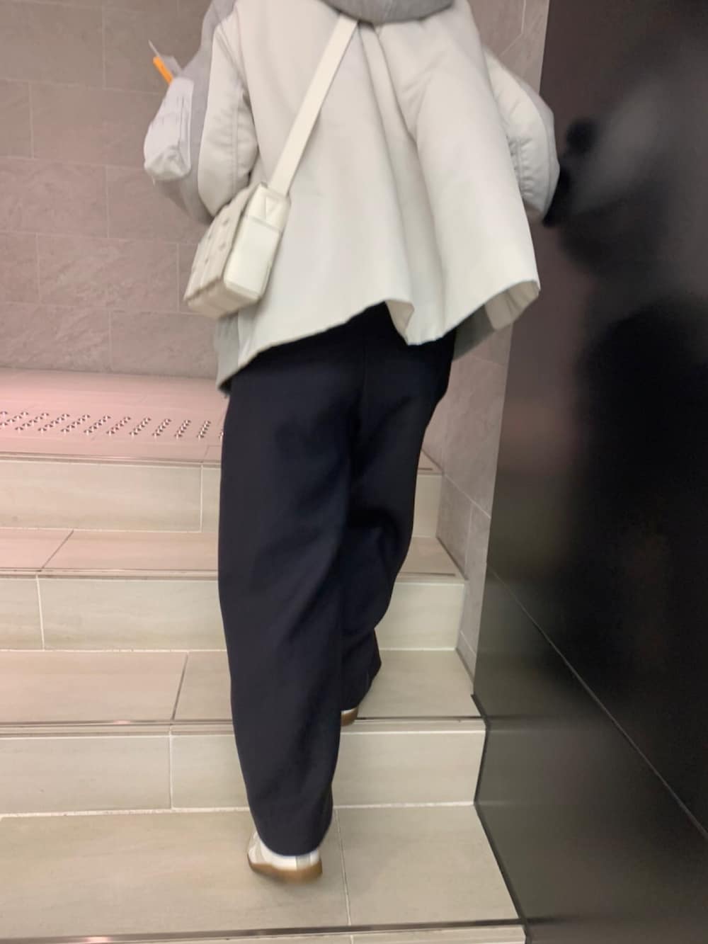 ブルー系のパンツ、グレー系のパーカー、ホワイト系のショルダーバッグを着用したレディースの冬コーディネートの2枚目の写真