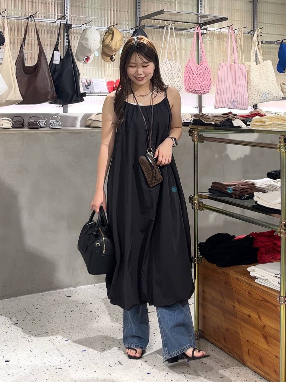 ベージュ系のキャミソール、ブラック系のワンピース、ブラック系のショルダーバッグを着用したレディースの夏コーディネートの3枚目の写真