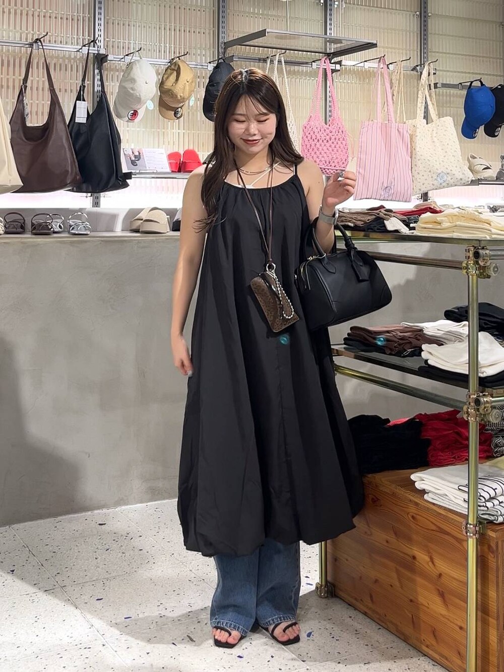 ベージュ系のキャミソール、ブラック系のワンピース、ブラック系のショルダーバッグを着用したレディースの夏コーディネートの2枚目の写真