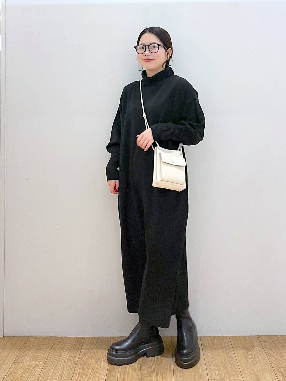 ホワイト系のショルダーバッグ、ブラック系のブーツ、ブラック系のワンピースを着用したレディースの冬コーディネートの4枚目の写真