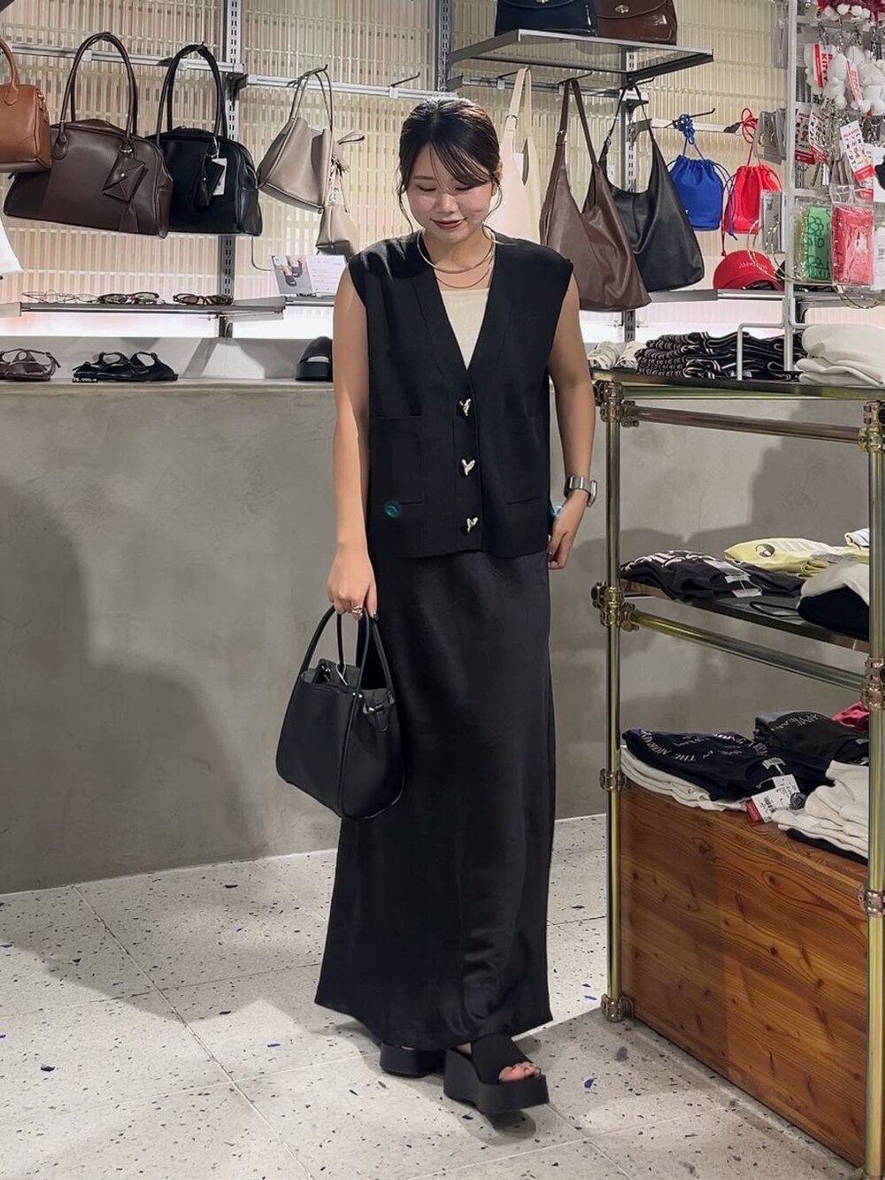 ブラック系のスカート、ブラック系のベスト、ブラック系のショルダーバッグを着用したレディースの夏コーディネートの2枚目の写真