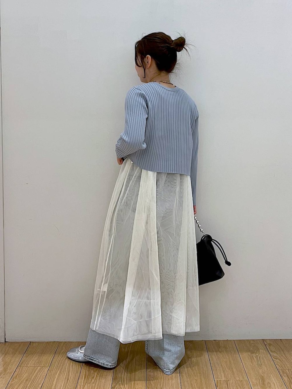 ブラック系のショルダーバッグ、ブルー系のデニムパンツ、ホワイト系のワンピースを着用したレディースの春コーディネートの3枚目の写真