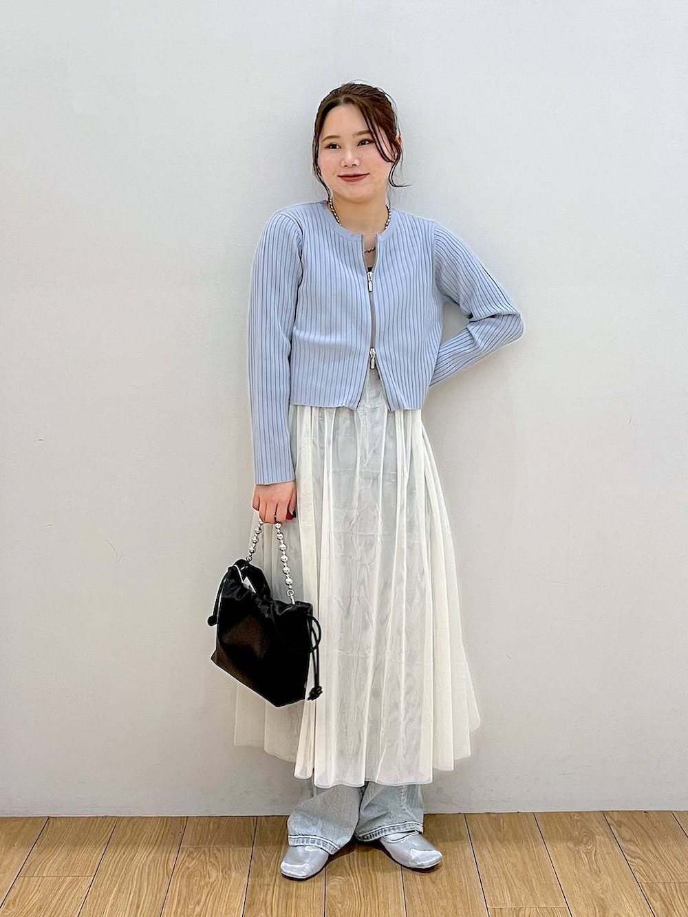 ブラック系のショルダーバッグ、ブルー系のデニムパンツ、ホワイト系のワンピースを着用したレディースの春コーディネートの5枚目の写真