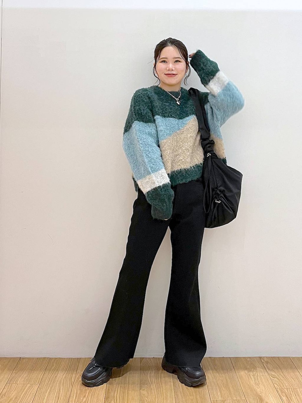 ブラック系のショルダーバッグ、グリーン系のニット/セーター、ブラック系のデニムパンツを着用したレディースの冬コーディネートの2枚目の写真