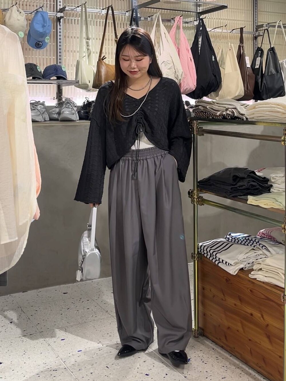 シルバー系のトートバッグ、シルバー系のパンプス、ブラック系のニット/セーターを着用したレディースの春コーディネートの2枚目の写真