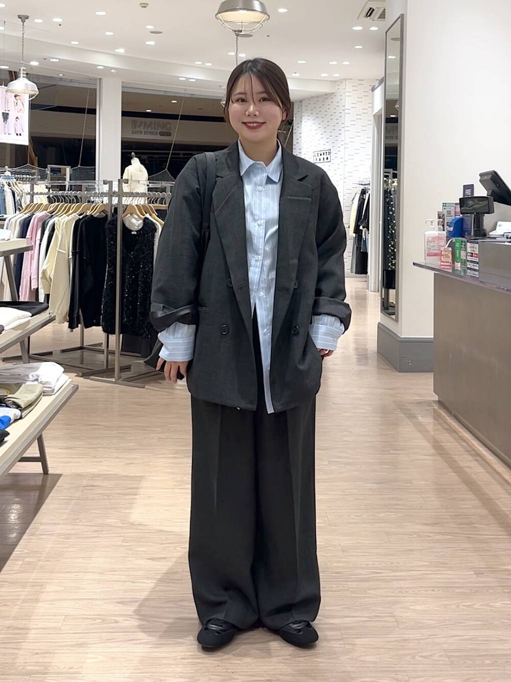ブラック系のショルダーバッグ、グレー系のスラックス、ブラック系のスニーカーを着用したレディースの冬コーディネートの2枚目の写真