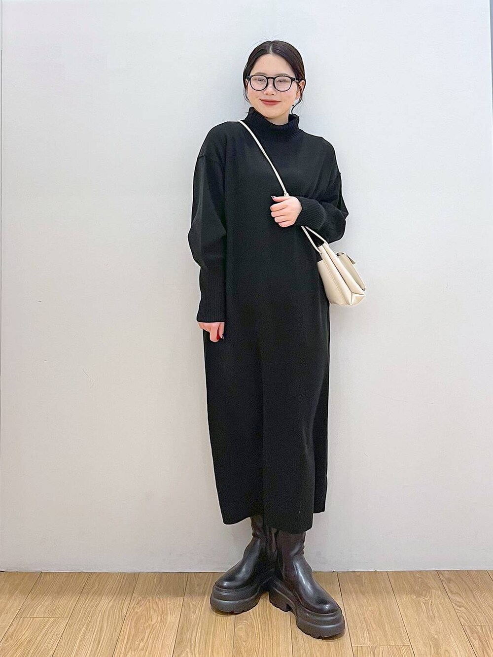 ホワイト系のショルダーバッグ、ブラック系のブーツ、ブラック系のワンピースを着用したレディースの冬コーディネートの3枚目の写真