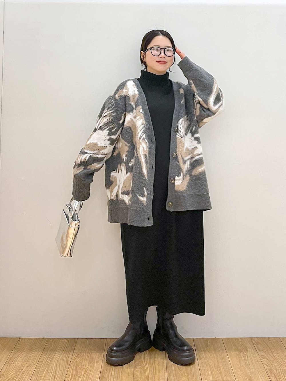 シルバー系のショルダーバッグ、ブラック系のワンピース、グレー系のカーディガン/ボレロを着用したレディースの冬コーディネートの2枚目の写真