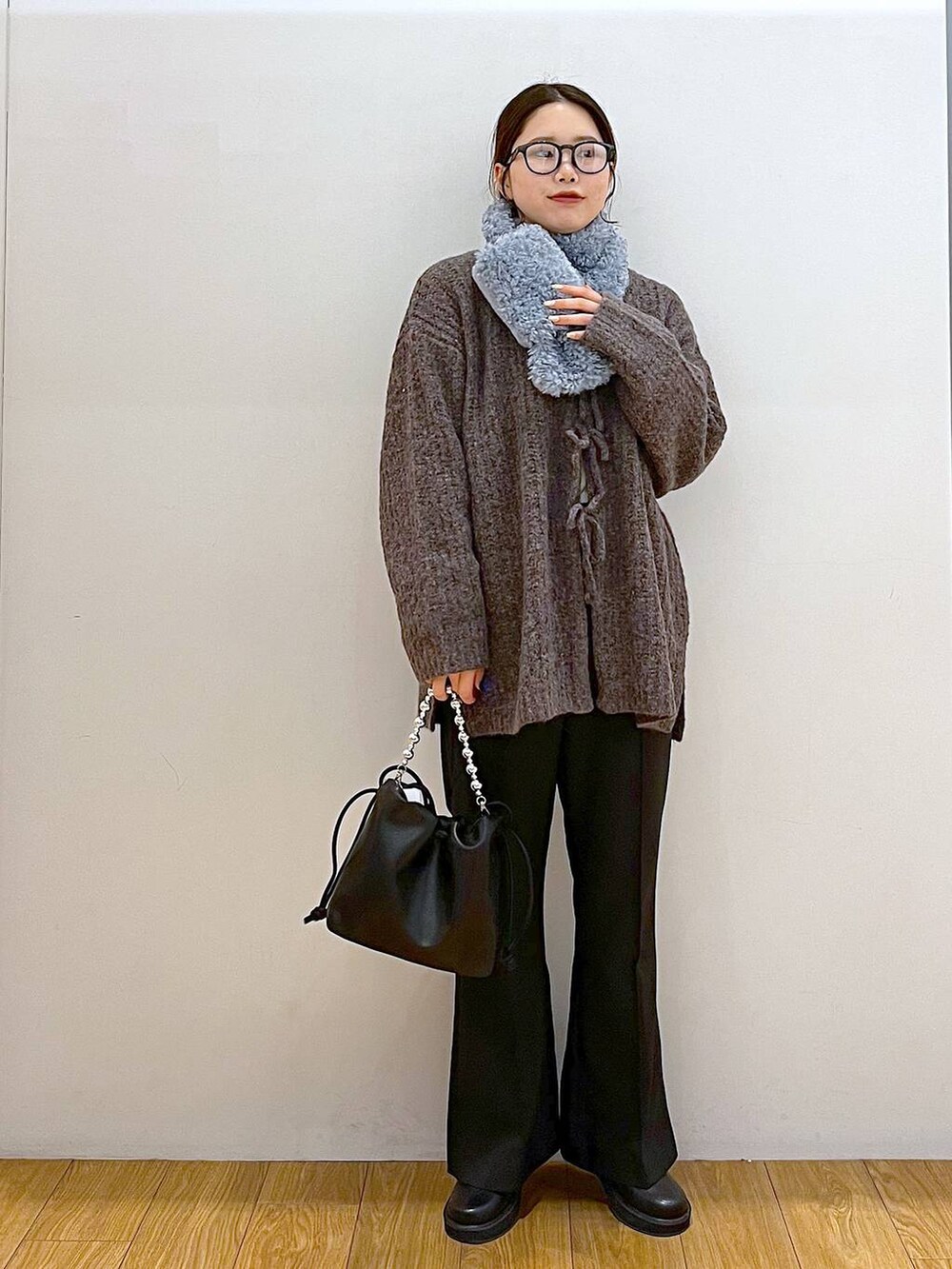 ブラック系のブーツ、ブラック系のスラックス、ブラック系のショルダーバッグを着用したレディースの冬コーディネートの3枚目の写真