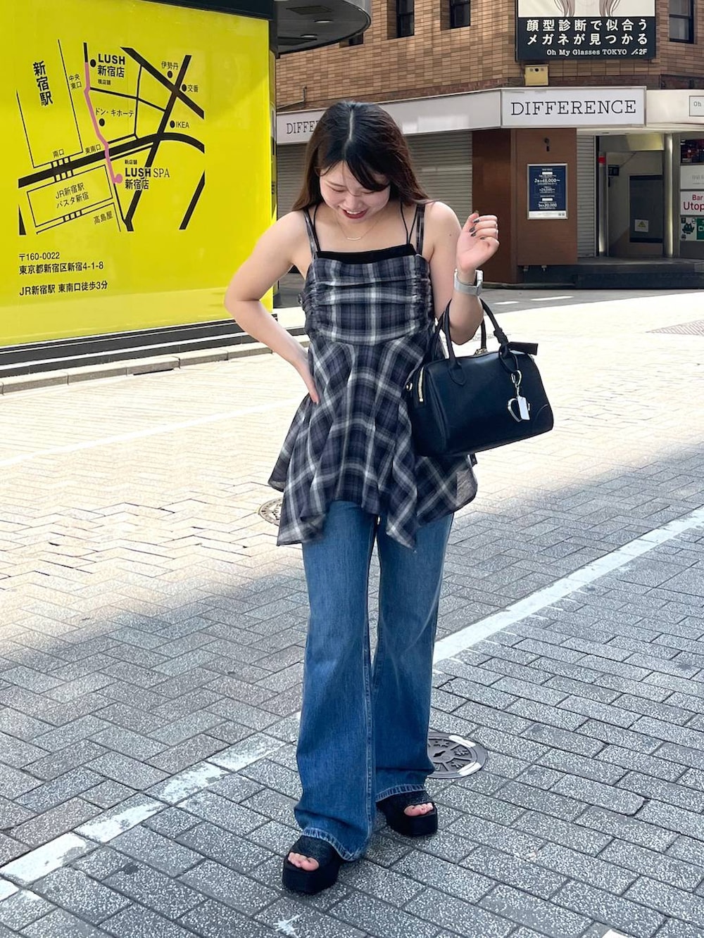 ブラック系のサンダル、ブラック系のショルダーバッグ、ブルー系のデニムパンツを着用したレディースの夏コーディネートの3枚目の写真