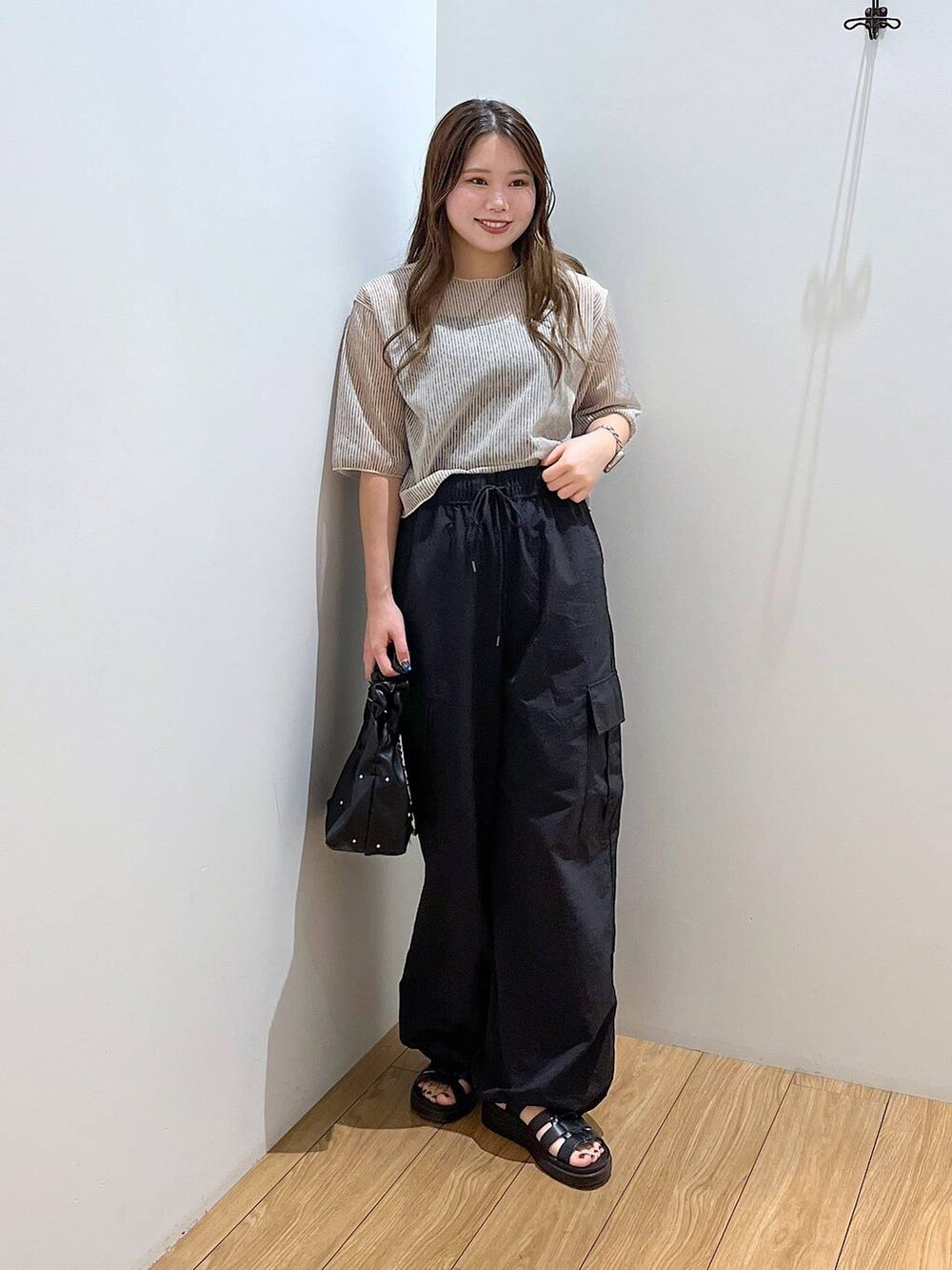 ブラック系のスニーカー、ホワイト系のTシャツ/カットソー、ブラック系のハンドバッグを着用したレディースの夏コーディネートの3枚目の写真