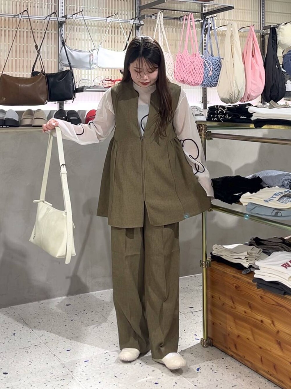 ブラウン系のスラックス、ブラウン系のベスト、ホワイト系のスニーカーを着用したレディースの春コーディネートの2枚目の写真