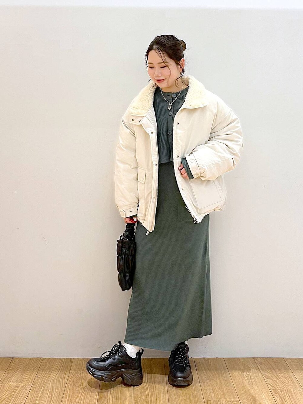 グリーン系のワンピース、ホワイト系のブルゾン、ブラック系のスニーカーを着用したレディースの冬コーディネートの3枚目の写真