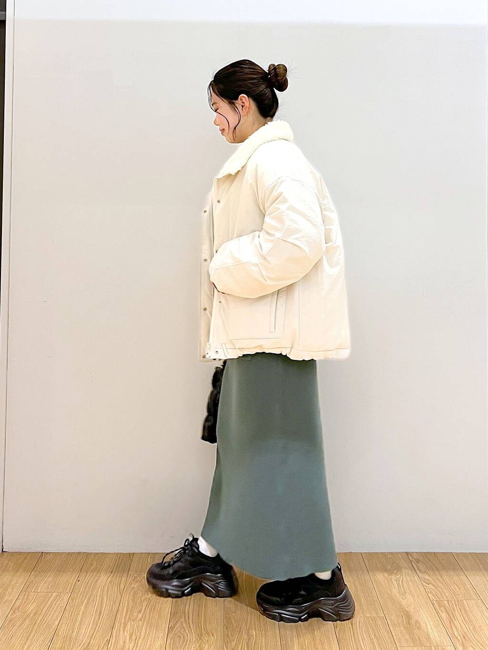 グリーン系のワンピース、ホワイト系のブルゾン、ブラック系のスニーカーを着用したレディースの冬コーディネートの4枚目の写真