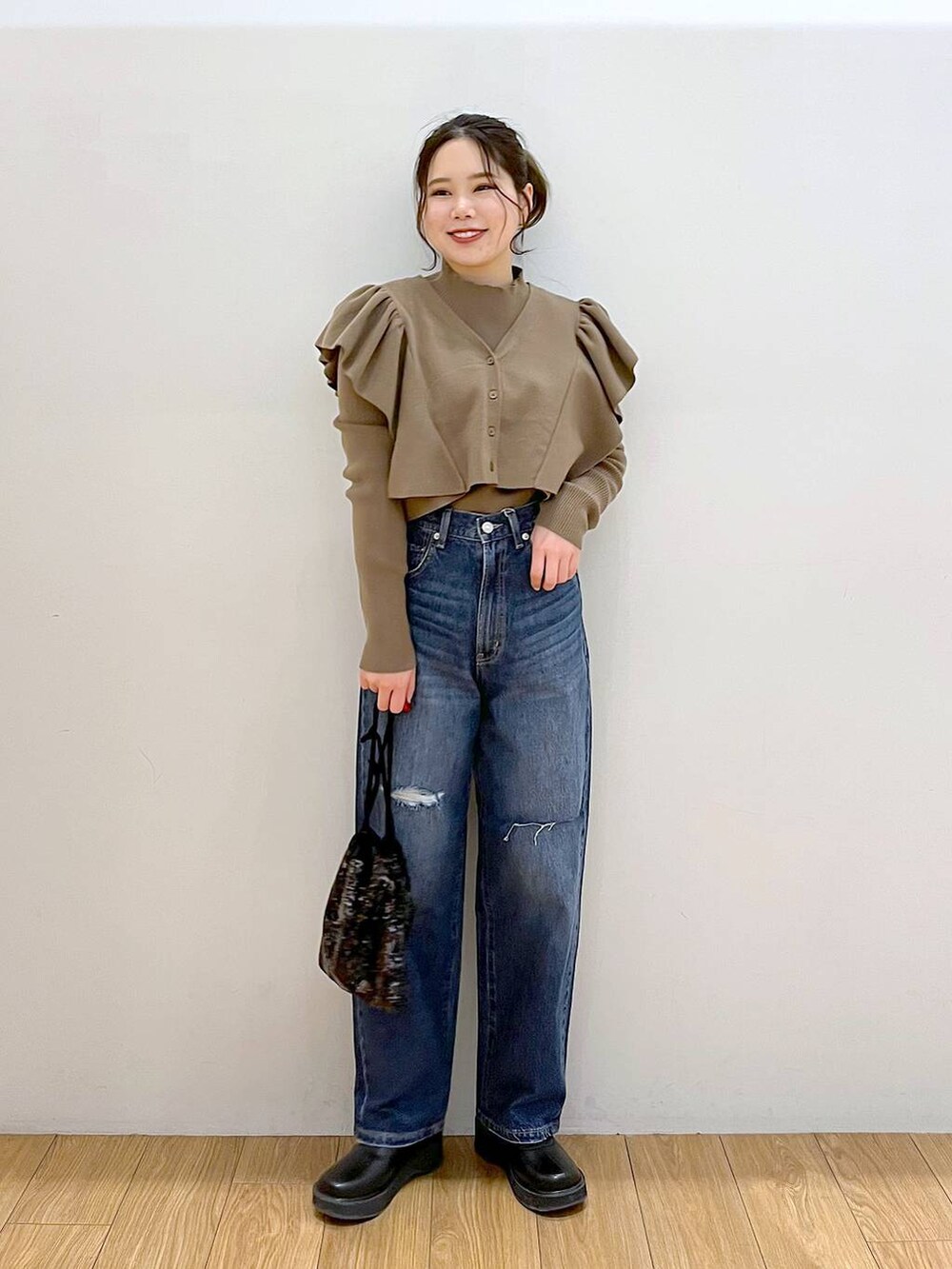 ブルー系のデニムパンツ、ブラック系のブーツ、ブラック系のハンドバッグを着用したレディースの冬コーディネートの2枚目の写真