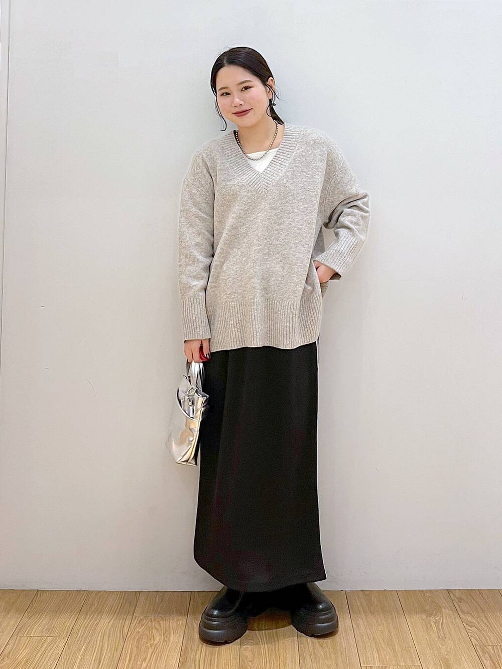 ホワイト系のTシャツ/カットソー、グレー系のニット/セーター、ブラック系のブーツを着用したレディースの冬コーディネートの2枚目の写真