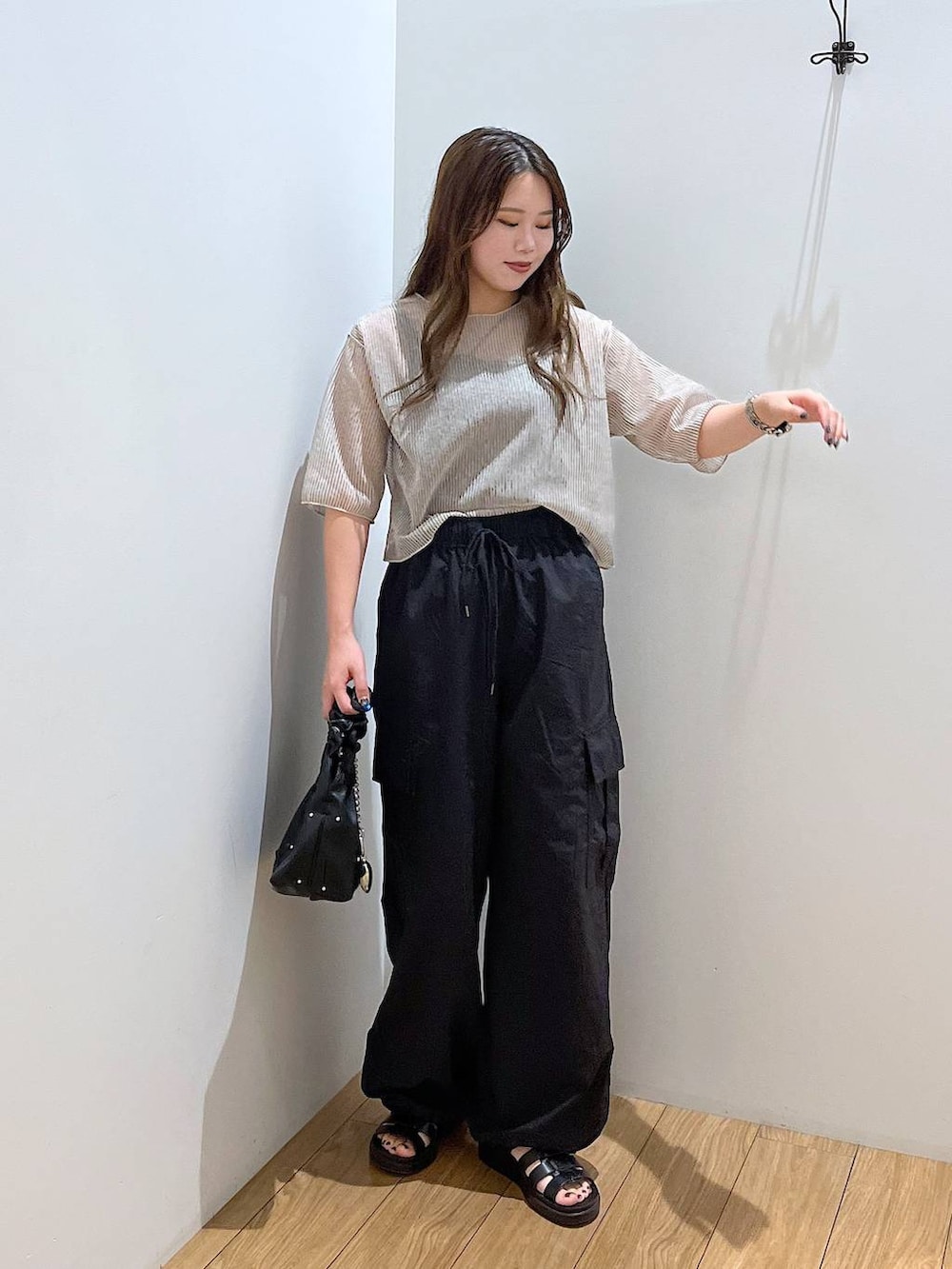 ブラック系のスニーカー、ホワイト系のTシャツ/カットソー、ブラック系のハンドバッグを着用したレディースの夏コーディネートの5枚目の写真