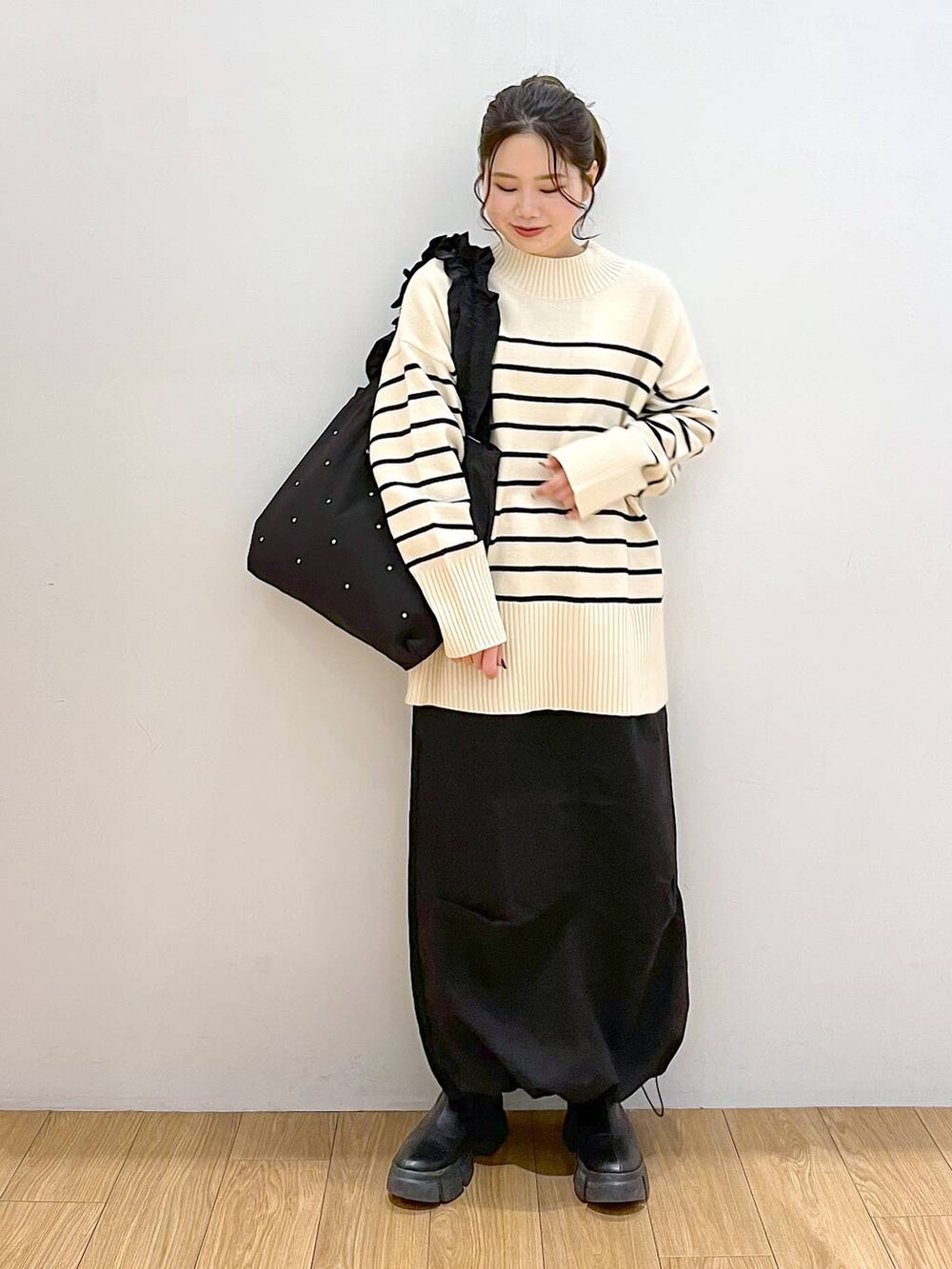 ブラック系のブーツ、その他のニット/セーター、ブラック系のトートバッグを着用したレディースの冬コーディネートの2枚目の写真