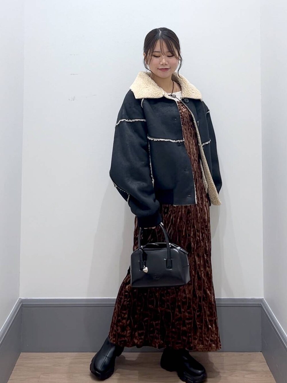 ブラック系のブーツ、ブラック系のボストンバッグ、ホワイト系のTシャツ/カットソーを着用したレディースの秋コーディネートの2枚目の写真