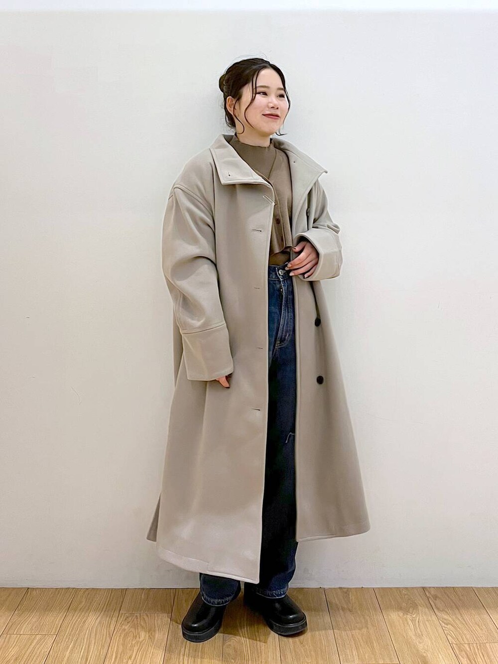 ブラウン系のチェスターコート、ブルー系のデニムパンツ、ブラック系のブーツを着用したレディースの冬コーディネートの2枚目の写真