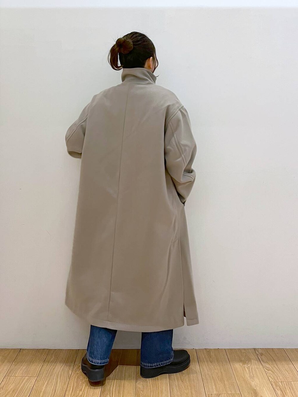 ブラウン系のチェスターコート、ブルー系のデニムパンツ、ブラック系のブーツを着用したレディースの冬コーディネートの4枚目の写真