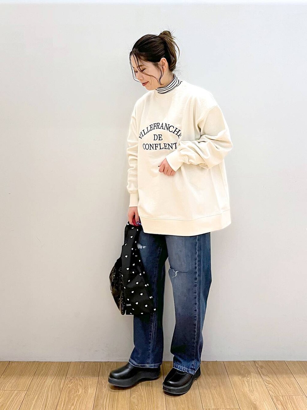 ホワイト系のTシャツ/カットソー、ブルー系のデニムパンツ、ブラック系のブーツを着用したレディースの冬コーディネートの4枚目の写真