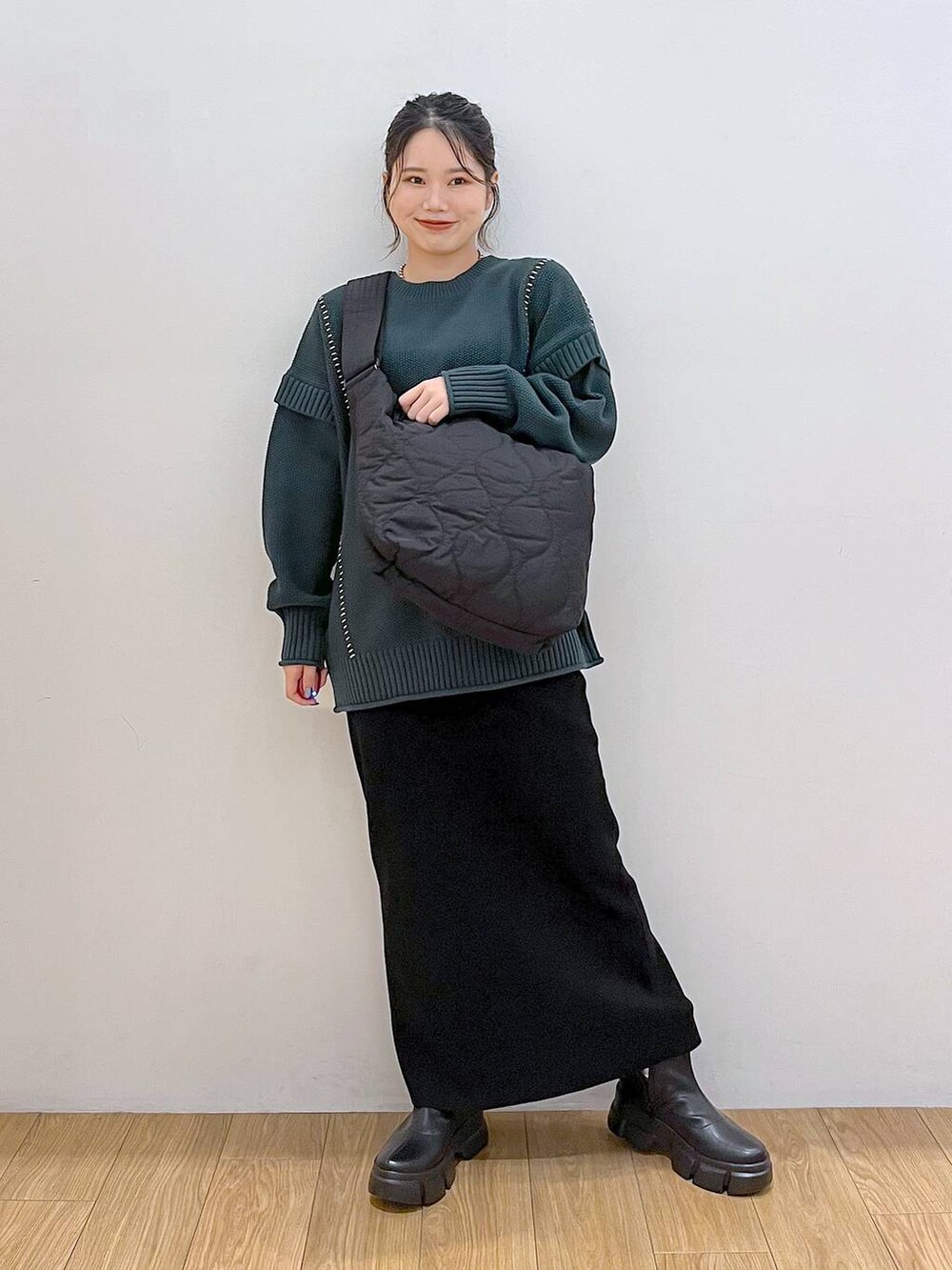 ブラック系のブーツ、ブラック系のショルダーバッグ、グリーン系のTシャツ/カットソーを着用したレディースの秋コーディネートの2枚目の写真