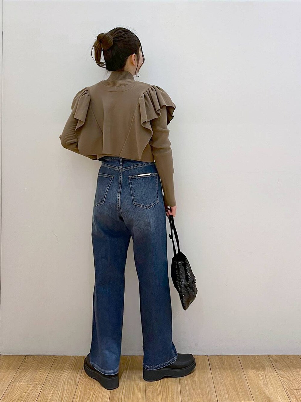 ブルー系のデニムパンツ、ブラック系のブーツ、ブラック系のハンドバッグを着用したレディースの冬コーディネートの3枚目の写真