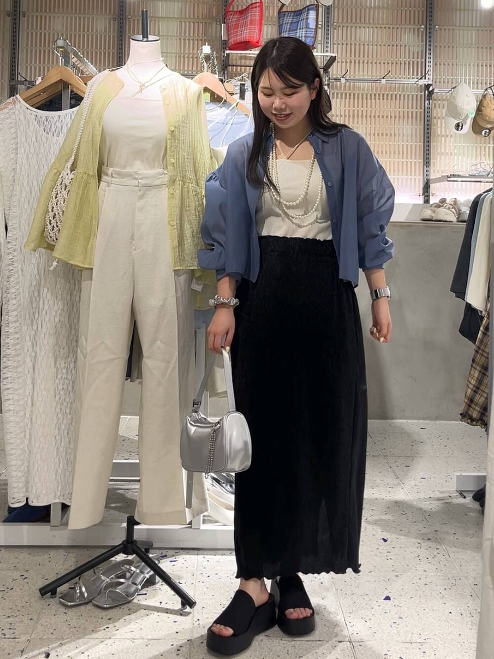 ブルー系のシャツ/ブラウス、ブラック系のサンダル、シルバー系のトートバッグを着用したレディースの春コーディネートの2枚目の写真