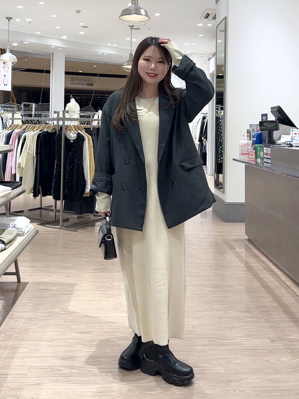 ブラック系のブーツ、ブラック系のショルダーバッグ、グレー系のテーラードジャケットを着用したレディースの冬コーディネートの2枚目の写真