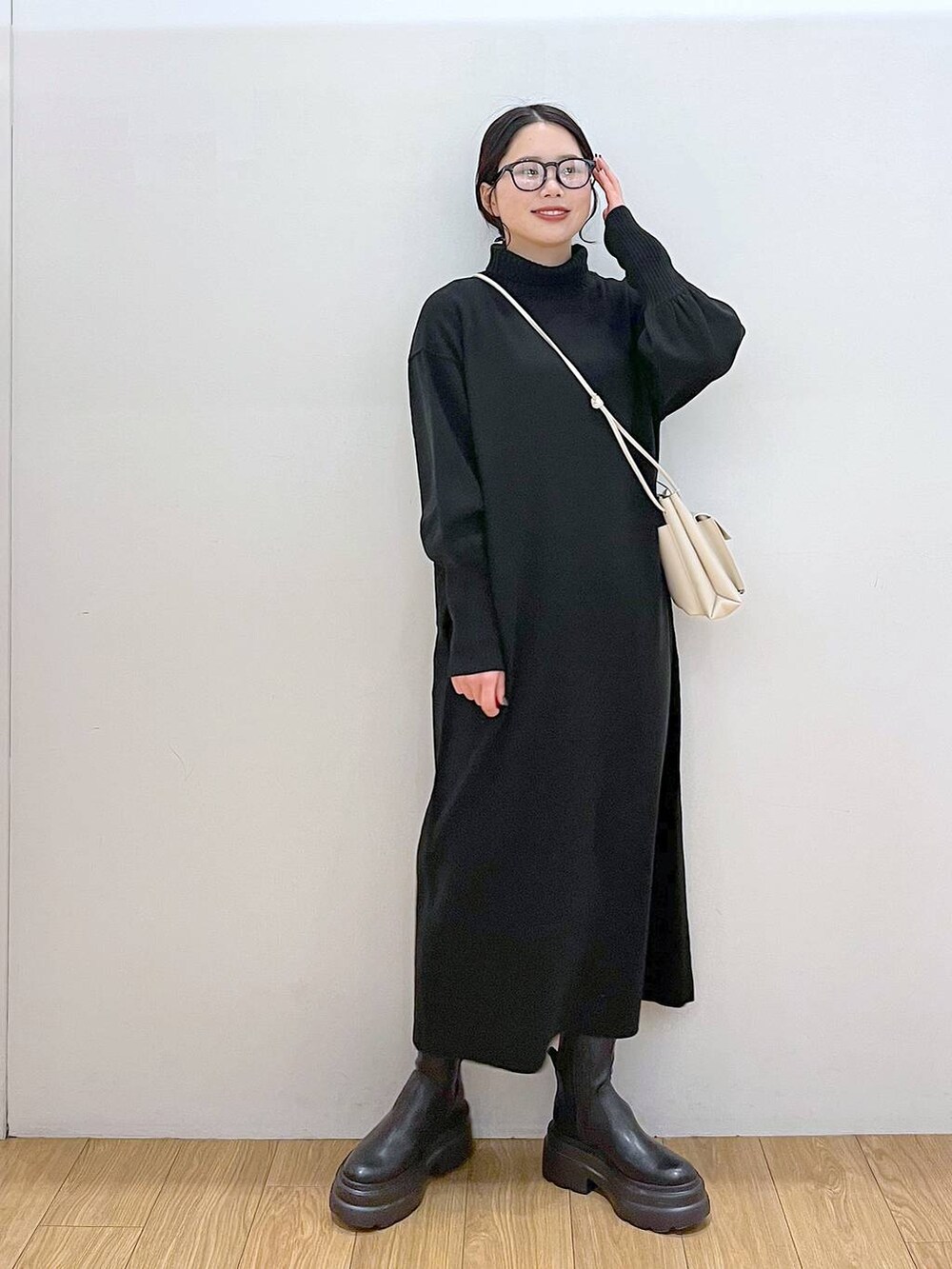 ホワイト系のショルダーバッグ、ブラック系のブーツ、ブラック系のワンピースを着用したレディースの冬コーディネートの2枚目の写真