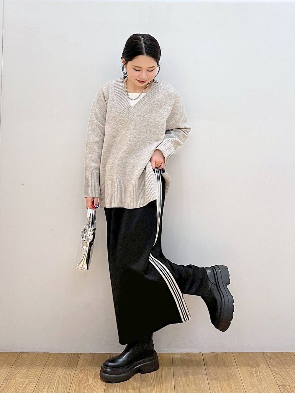 ホワイト系のTシャツ/カットソー、グレー系のニット/セーター、ブラック系のブーツを着用したレディースの冬コーディネートの4枚目の写真