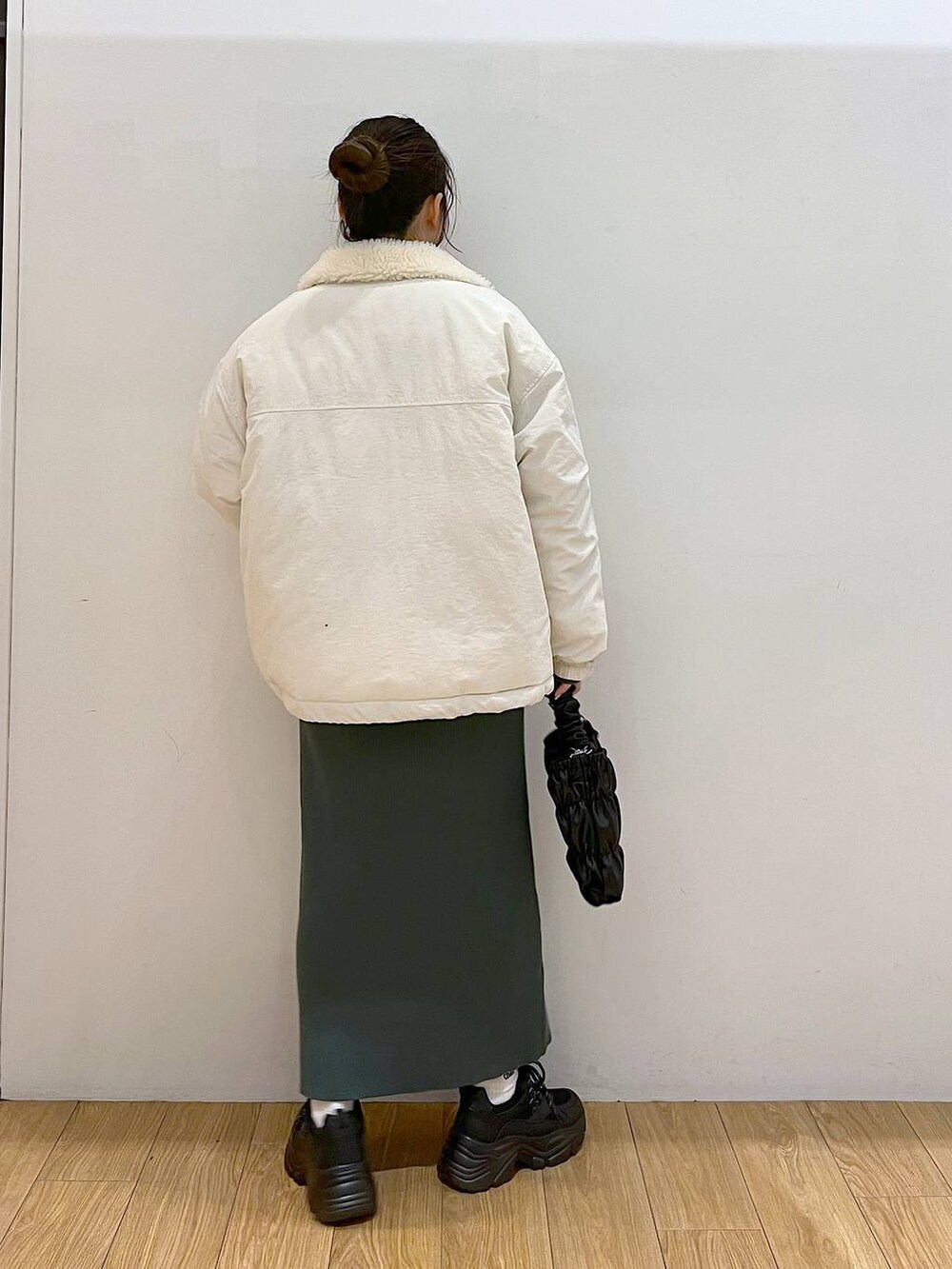 グリーン系のワンピース、ホワイト系のブルゾン、ブラック系のスニーカーを着用したレディースの冬コーディネートの5枚目の写真