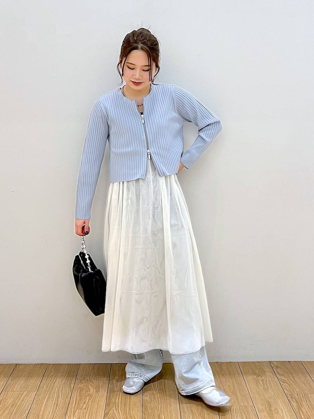 ブラック系のショルダーバッグ、ブルー系のデニムパンツ、ホワイト系のワンピースを着用したレディースの春コーディネートの2枚目の写真