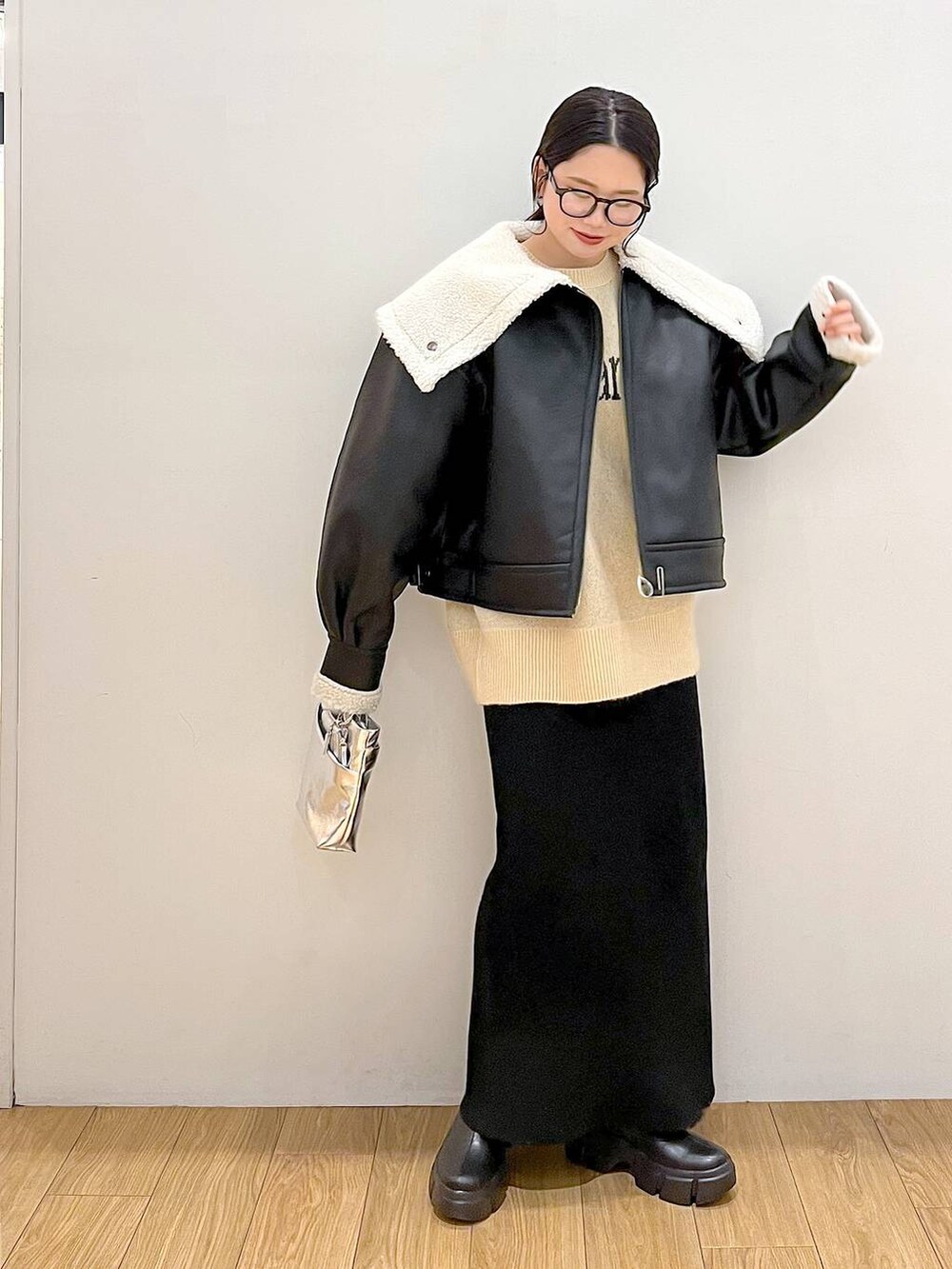 シルバー系のショルダーバッグ、ブラック系のブルゾン、ブラック系のスカートを着用したレディースの冬コーディネートの2枚目の写真