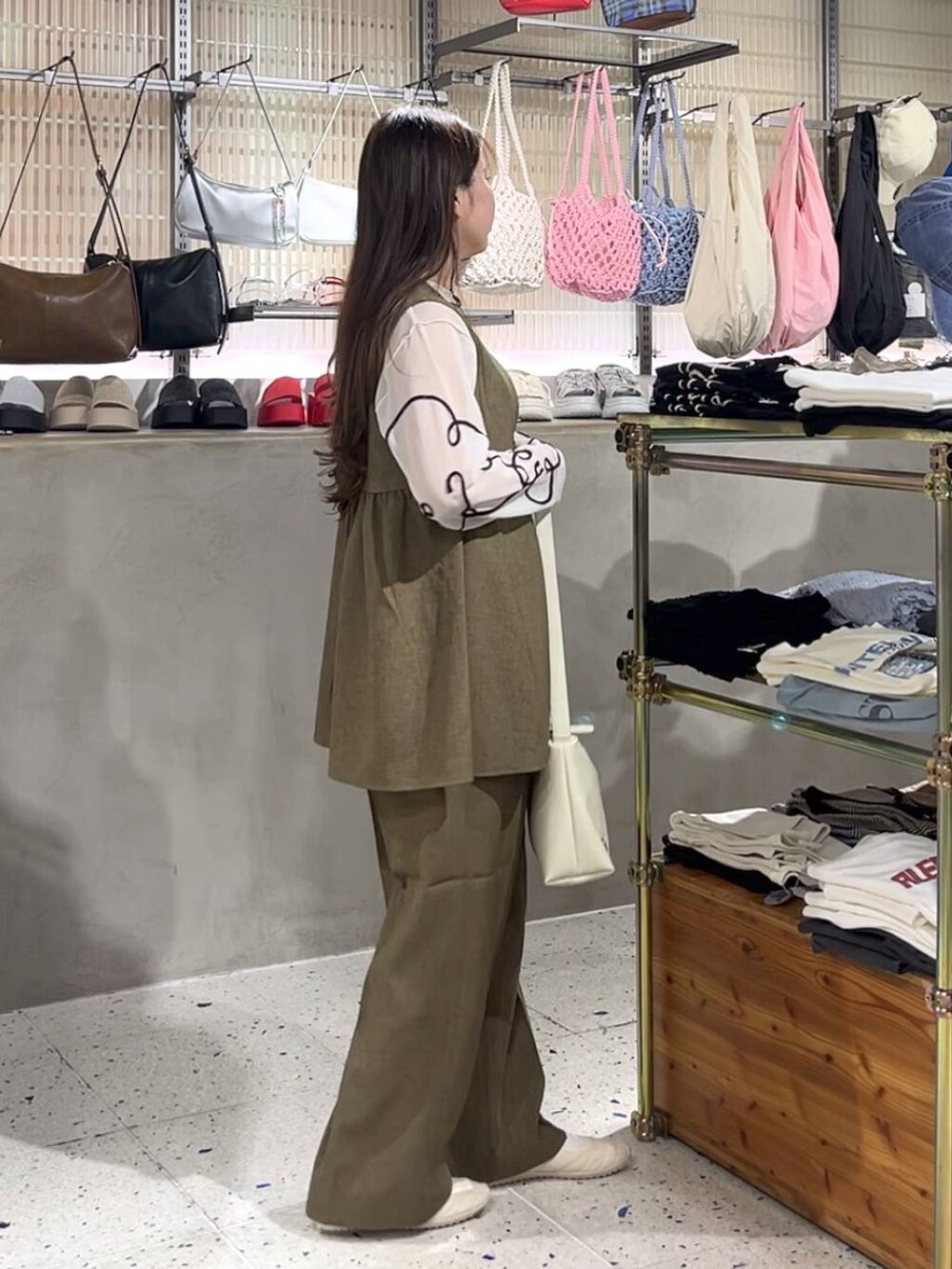 ブラウン系のスラックス、ブラウン系のベスト、ホワイト系のスニーカーを着用したレディースの春コーディネートの4枚目の写真