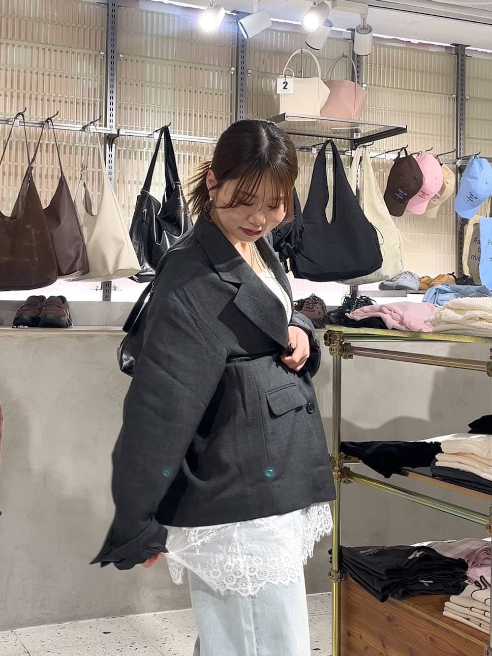 グレー系のテーラードジャケット、ブルー系のデニムパンツ、ブラック系のショルダーバッグを着用したレディースの春コーディネートの2枚目の写真