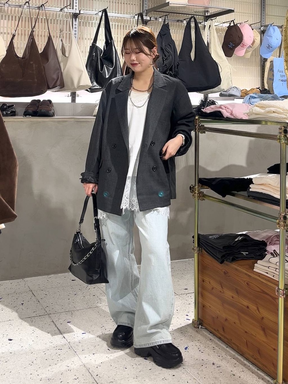 グレー系のテーラードジャケット、ブルー系のデニムパンツ、ブラック系のショルダーバッグを着用したレディースの春コーディネートの3枚目の写真