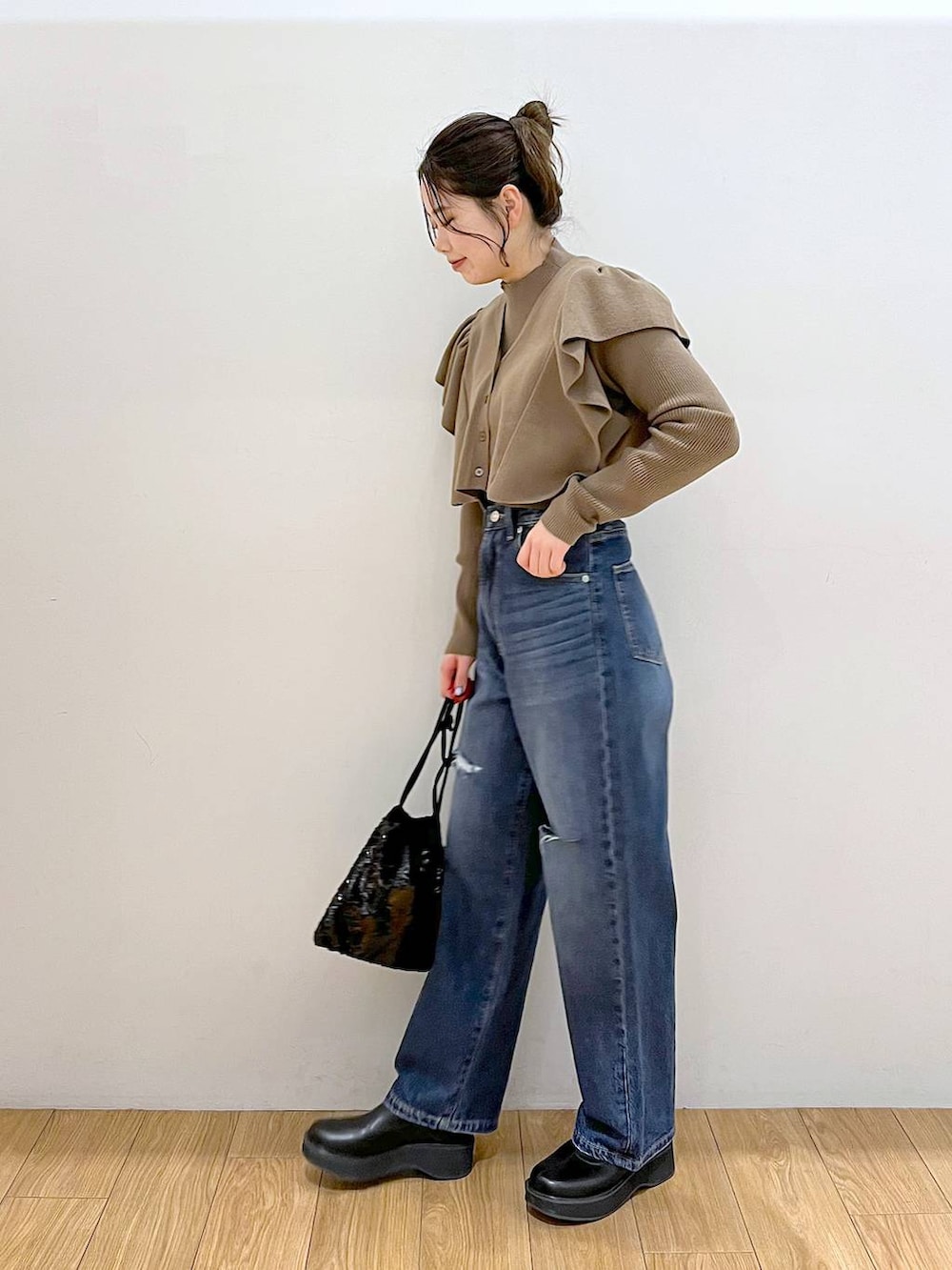 ブルー系のデニムパンツ、ブラック系のブーツ、ブラック系のハンドバッグを着用したレディースの冬コーディネートの4枚目の写真