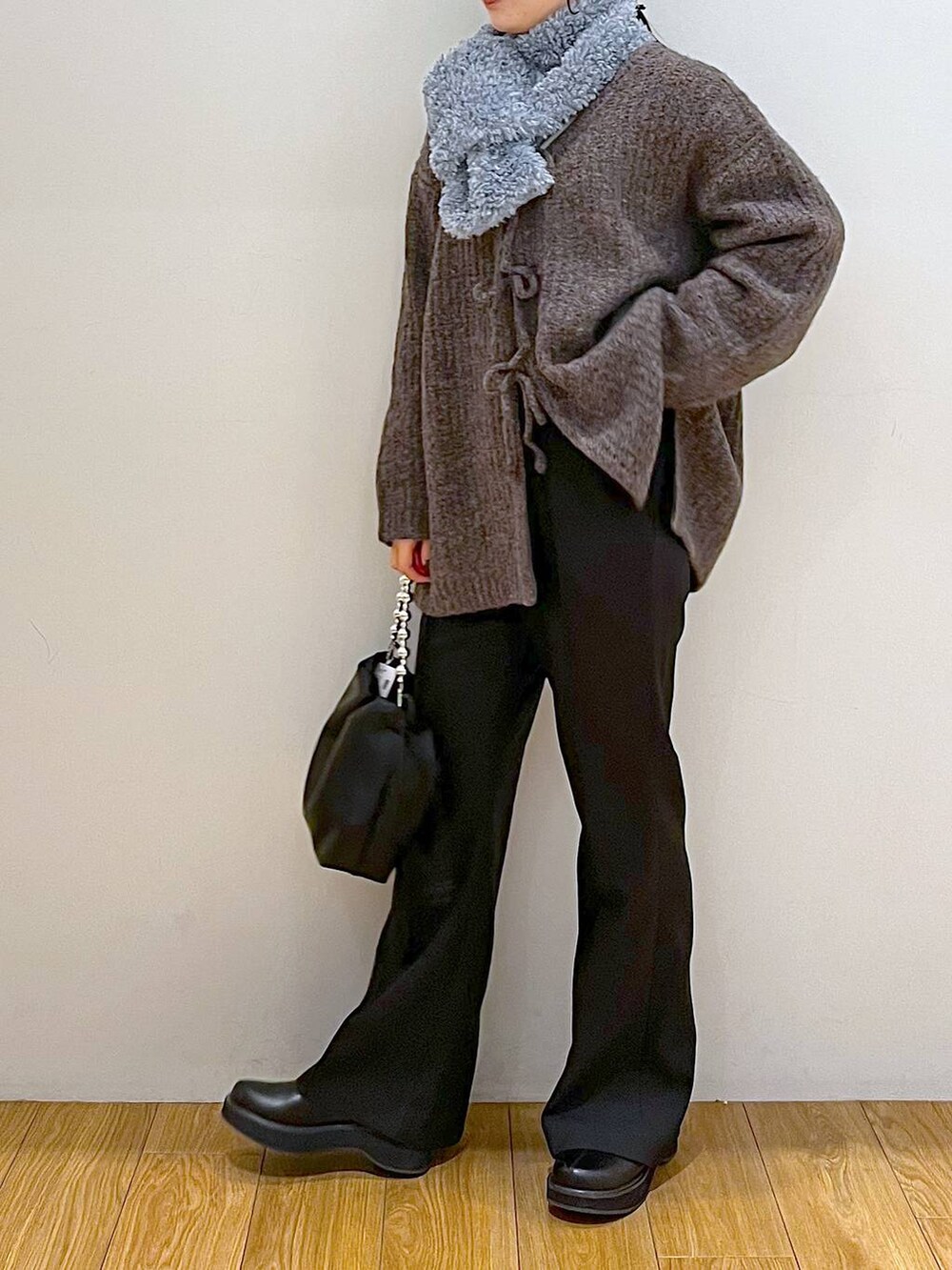 ブラック系のブーツ、ブラック系のスラックス、ブラック系のショルダーバッグを着用したレディースの冬コーディネートの4枚目の写真