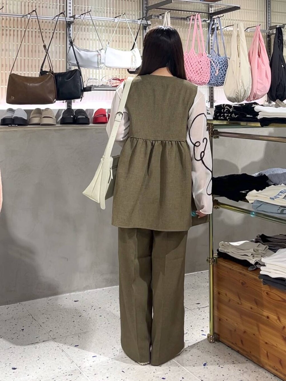 ブラウン系のスラックス、ブラウン系のベスト、ホワイト系のスニーカーを着用したレディースの春コーディネートの3枚目の写真