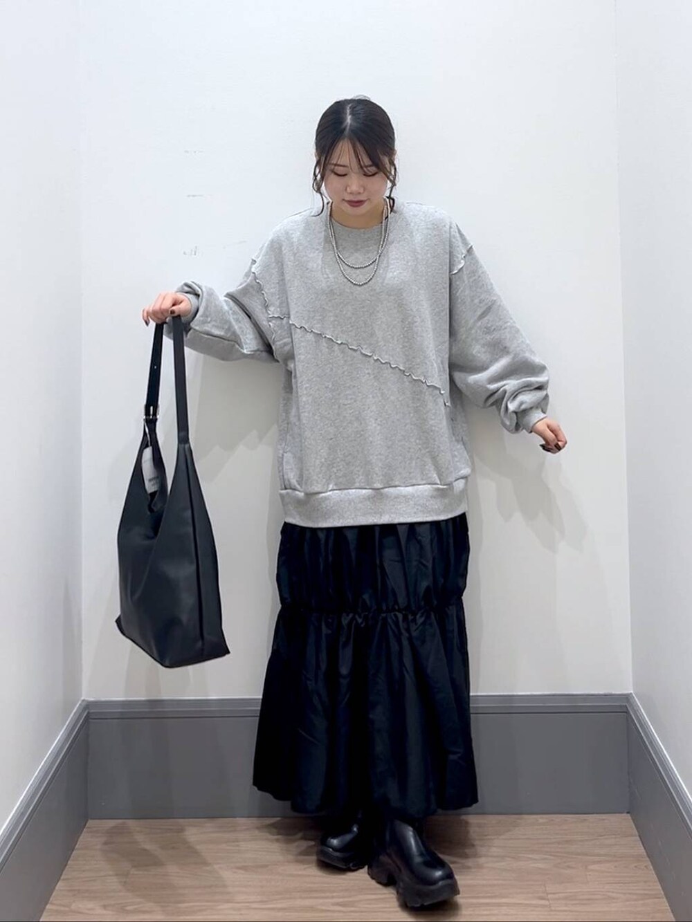 ブラック系のショルダーバッグ、ブラック系のブーツ、グレー系のワンピースを着用したレディースの秋コーディネートの2枚目の写真