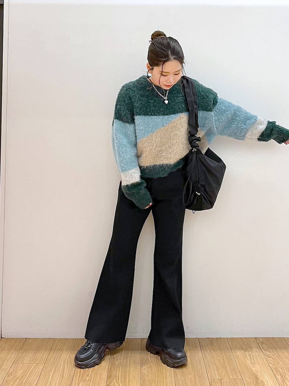 ブラック系のショルダーバッグ、グリーン系のニット/セーター、ブラック系のデニムパンツを着用したレディースの冬コーディネートの3枚目の写真