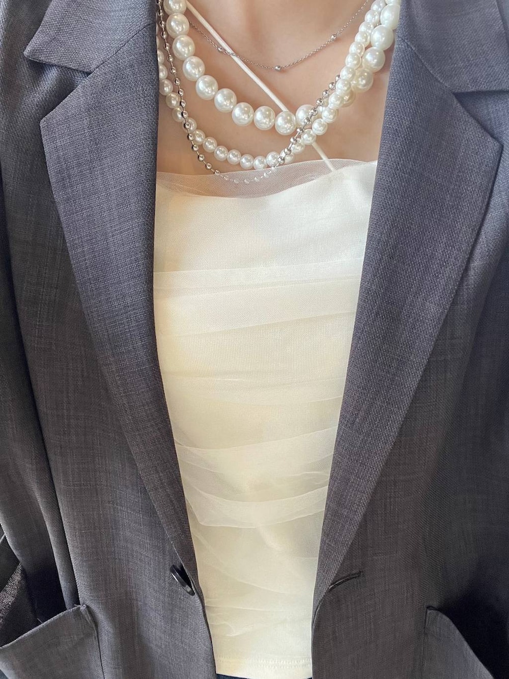 ベージュ系のテーラードジャケット、ベージュ系のネックレスを着用したレディースの春コーディネートの4枚目の写真