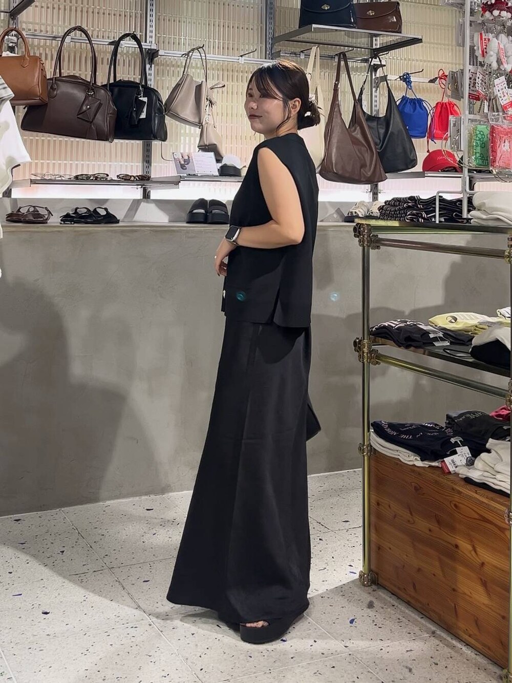 ブラック系のスカート、ブラック系のベスト、ブラック系のショルダーバッグを着用したレディースの夏コーディネートの4枚目の写真