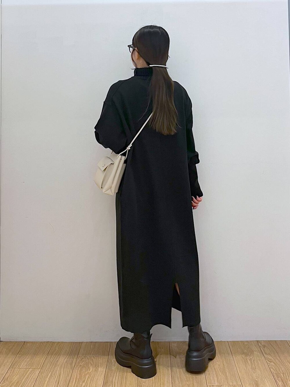 ホワイト系のショルダーバッグ、ブラック系のブーツ、ブラック系のワンピースを着用したレディースの冬コーディネートの5枚目の写真