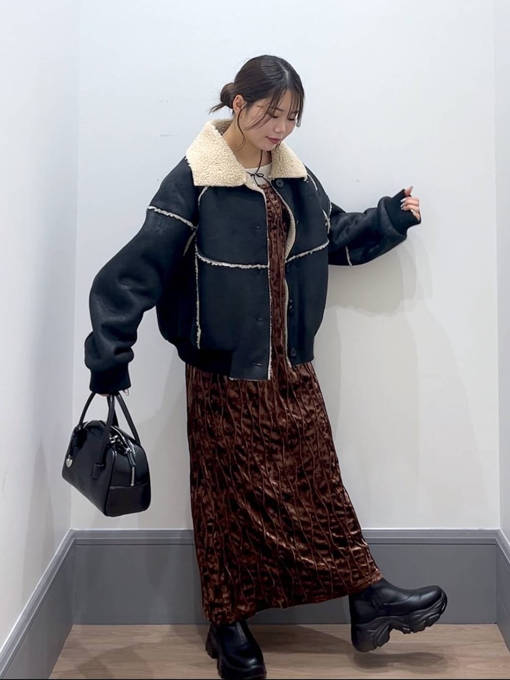 ブラック系のブーツ、ブラック系のボストンバッグ、ホワイト系のTシャツ/カットソーを着用したレディースの秋コーディネートの3枚目の写真