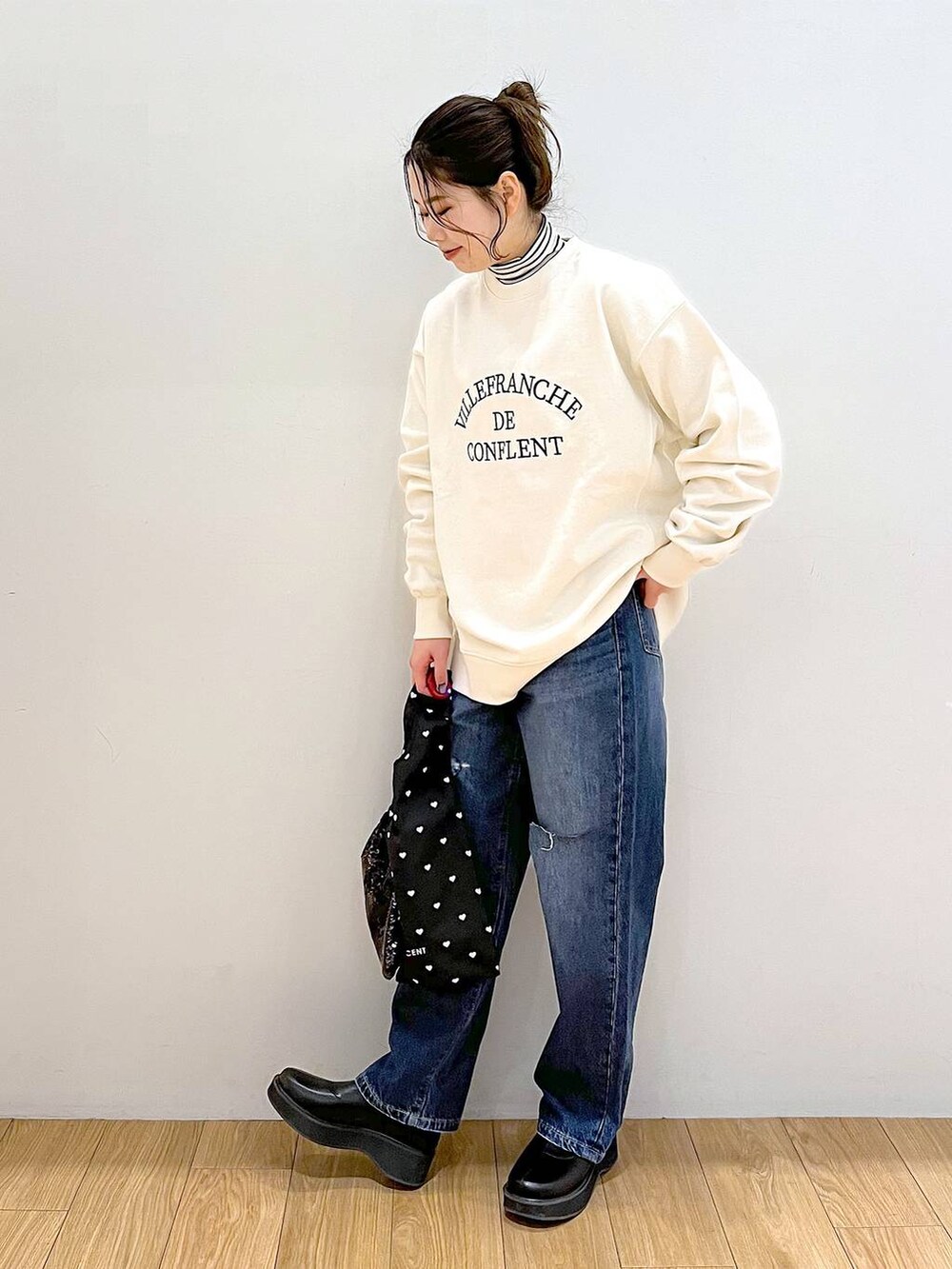 ホワイト系のTシャツ/カットソー、ブルー系のデニムパンツ、ブラック系のブーツを着用したレディースの冬コーディネートの2枚目の写真