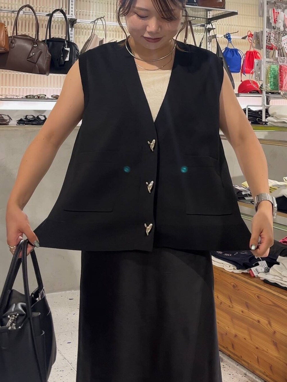 ブラック系のスカート、ブラック系のベスト、ブラック系のショルダーバッグを着用したレディースの夏コーディネートの3枚目の写真